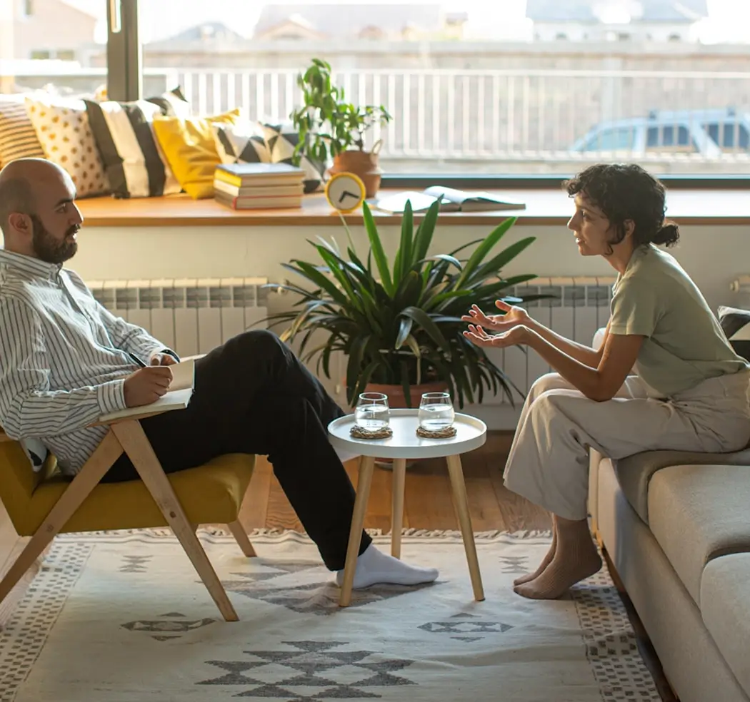 Man taking notes listens as woman speaks in living-room conversation